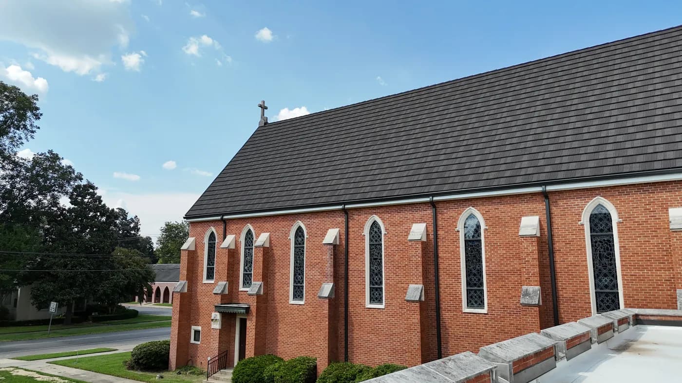 Brick church with new stone-coated steel shake-profile roof and small cross at peak